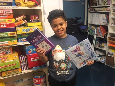 NHR student happily displays books he received in the giveaway.