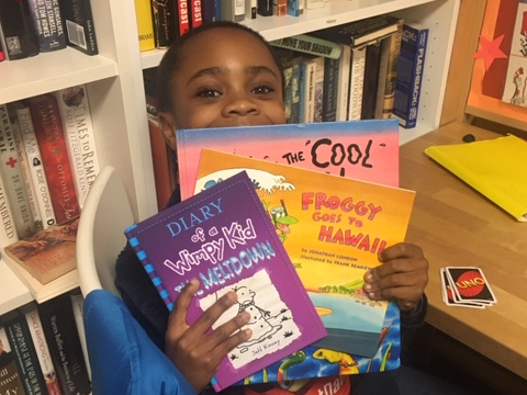 NHR student happily displays books he received in the giveaway.