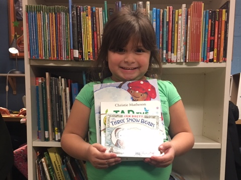 NHR student happily displays books she received in the giveaway.