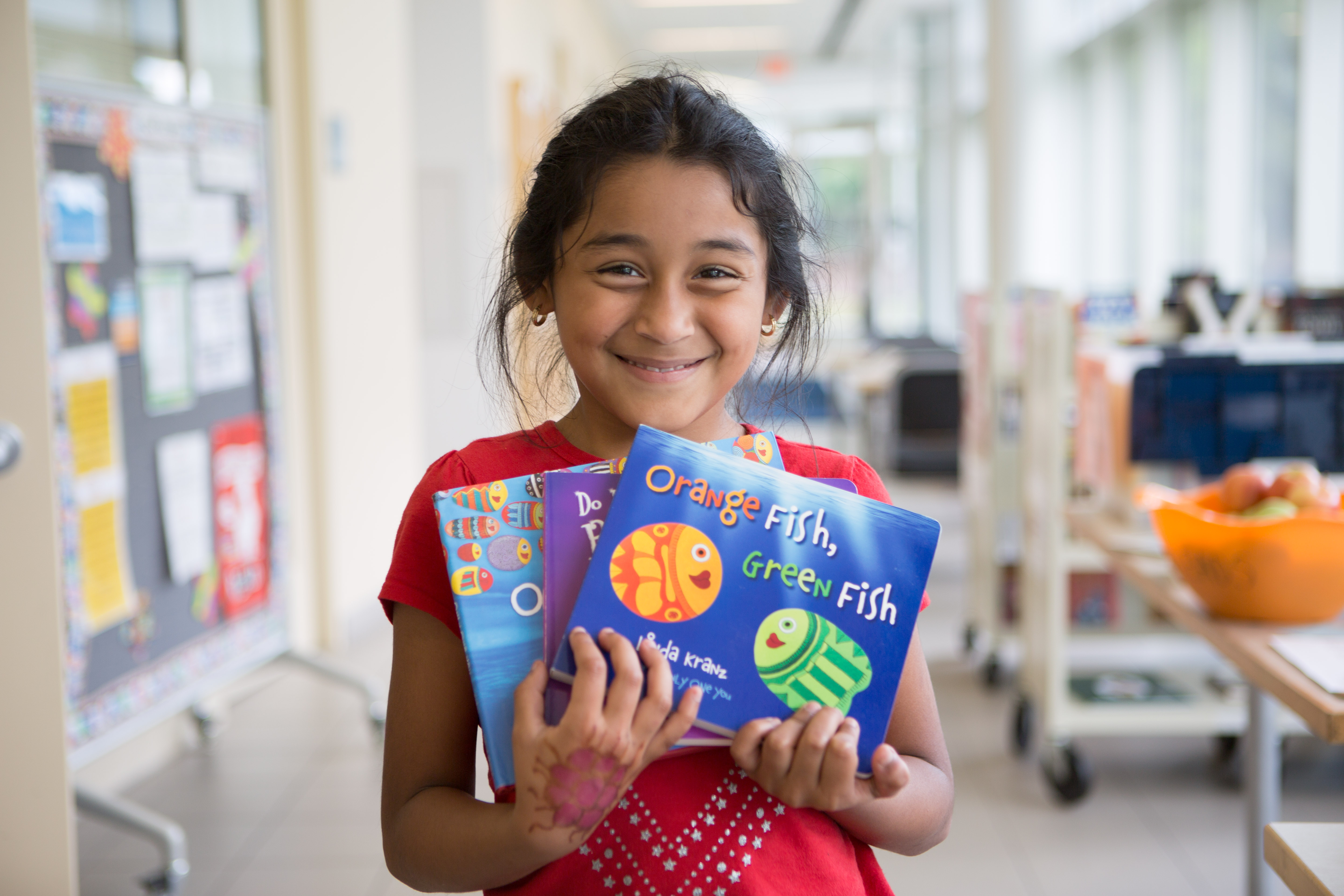 Smiling NHR student displays books she received in a giveaway.