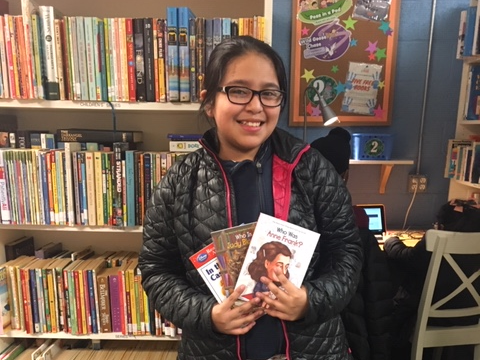 NHR student happily displays books she received in the giveaway.