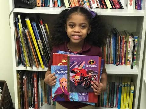 NHR student happily displays books she received in the giveaway.