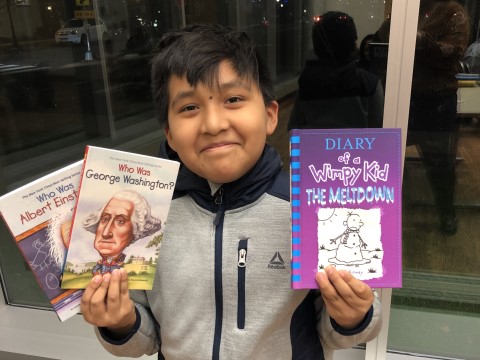 NHR student happily displays books he received in the giveaway.