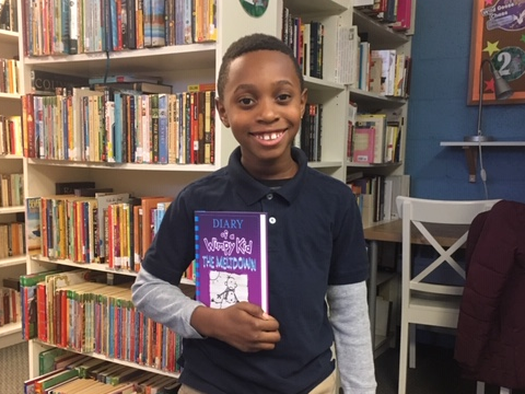 NHR student happily displays a book he received in the giveaway.