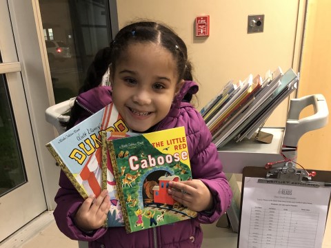 NHR student happily displays a books she received in the giveaway.