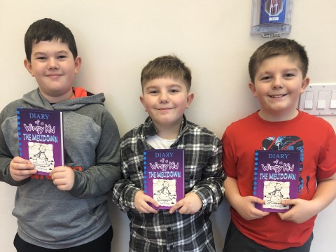 NHR students happily display a book they received in the giveaway.