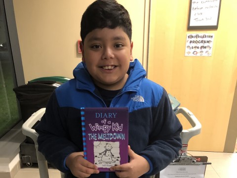 NHR student happily displays a book he received in the giveaway.