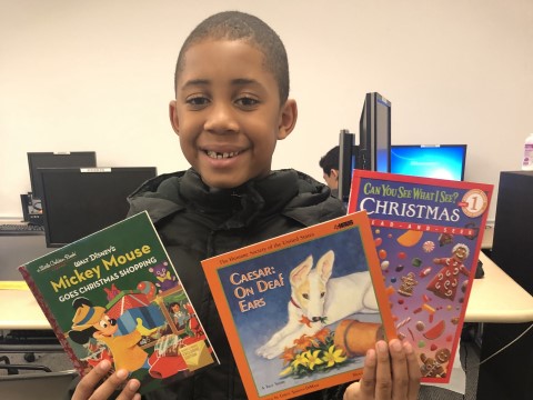 NHR student happily displays books he received in the giveaway.