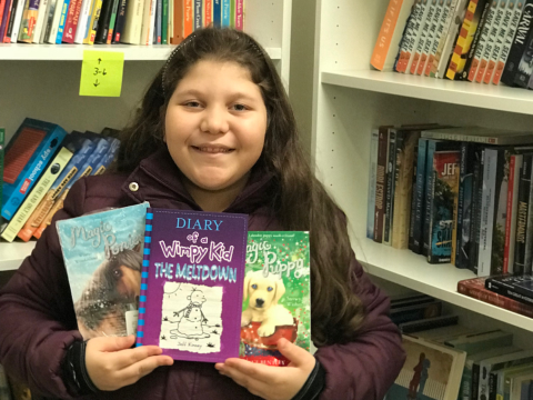 NHR student happily displays a books she received in the giveaway.