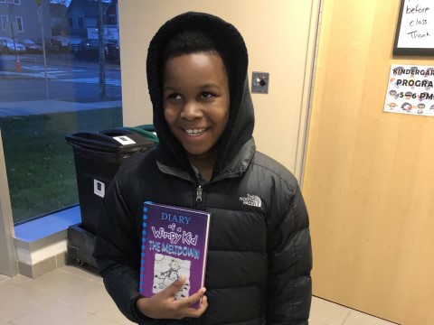 NHR student happily displays a book he received in the giveaway.