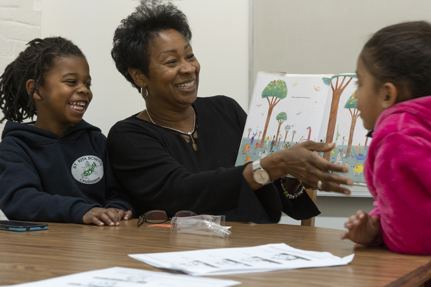 Two students enjoy reading a popular children's book with their tutor.