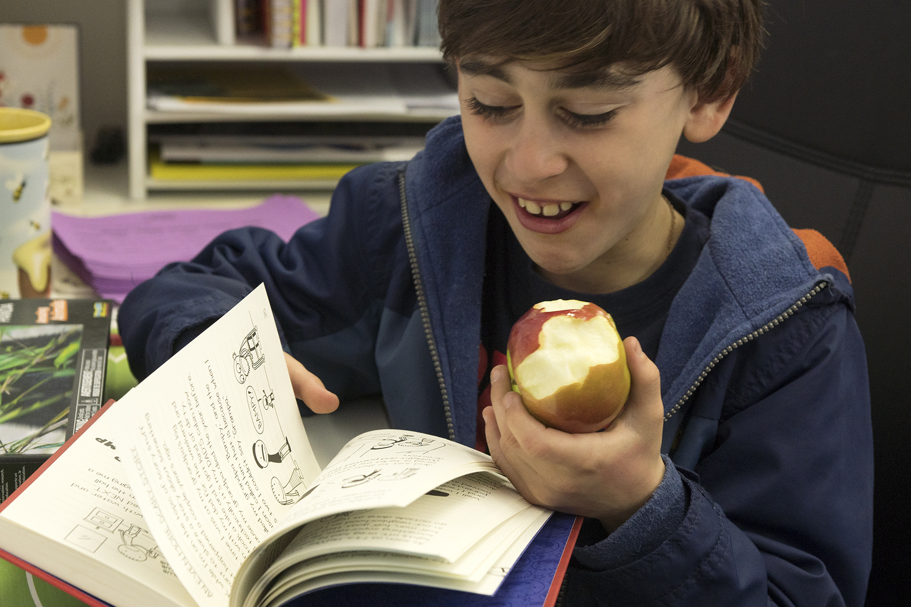 Student reading a chapter book and eating an apple