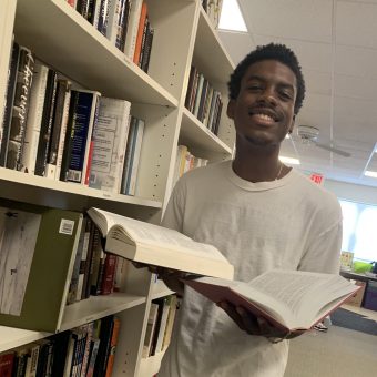A student smiles holding two books.